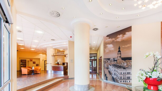 A hotel lobby with a reception desk, seating area, and a large mural of a cityscape.