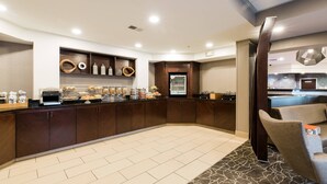 A modern kitchen with a built-in coffee station, a refrigerator, and a seating area with a patterned rug.