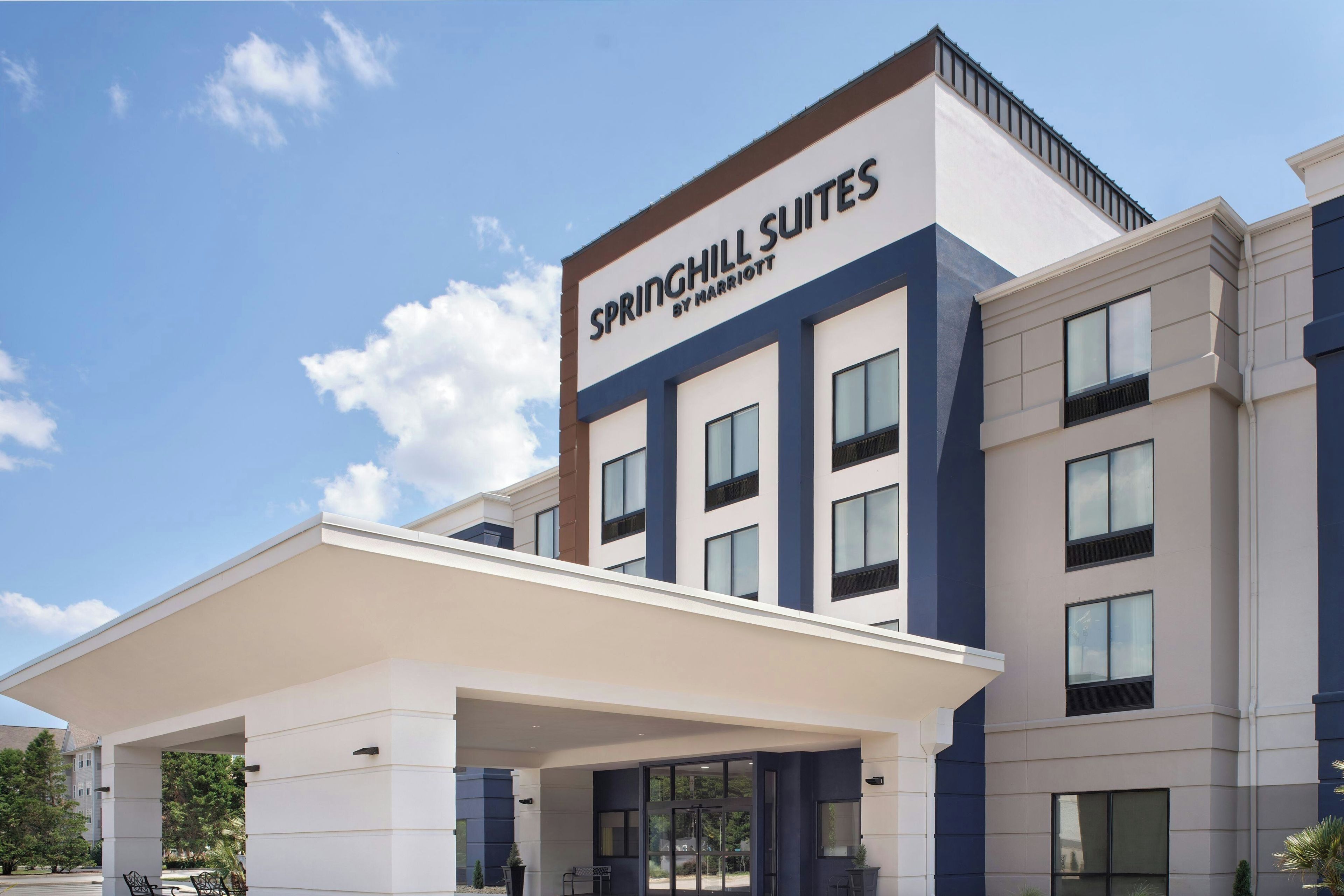 Een hotel met een moderne gevel, een overdekte ingang en een bord met de tekst 'SPRINGHILL SUITES BY MARRIOTT'.