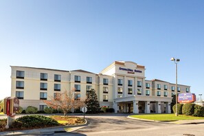 Un hotel SpringHill Suites Marriott con una fachada moderna, varias ventanas y un cielo despejado.