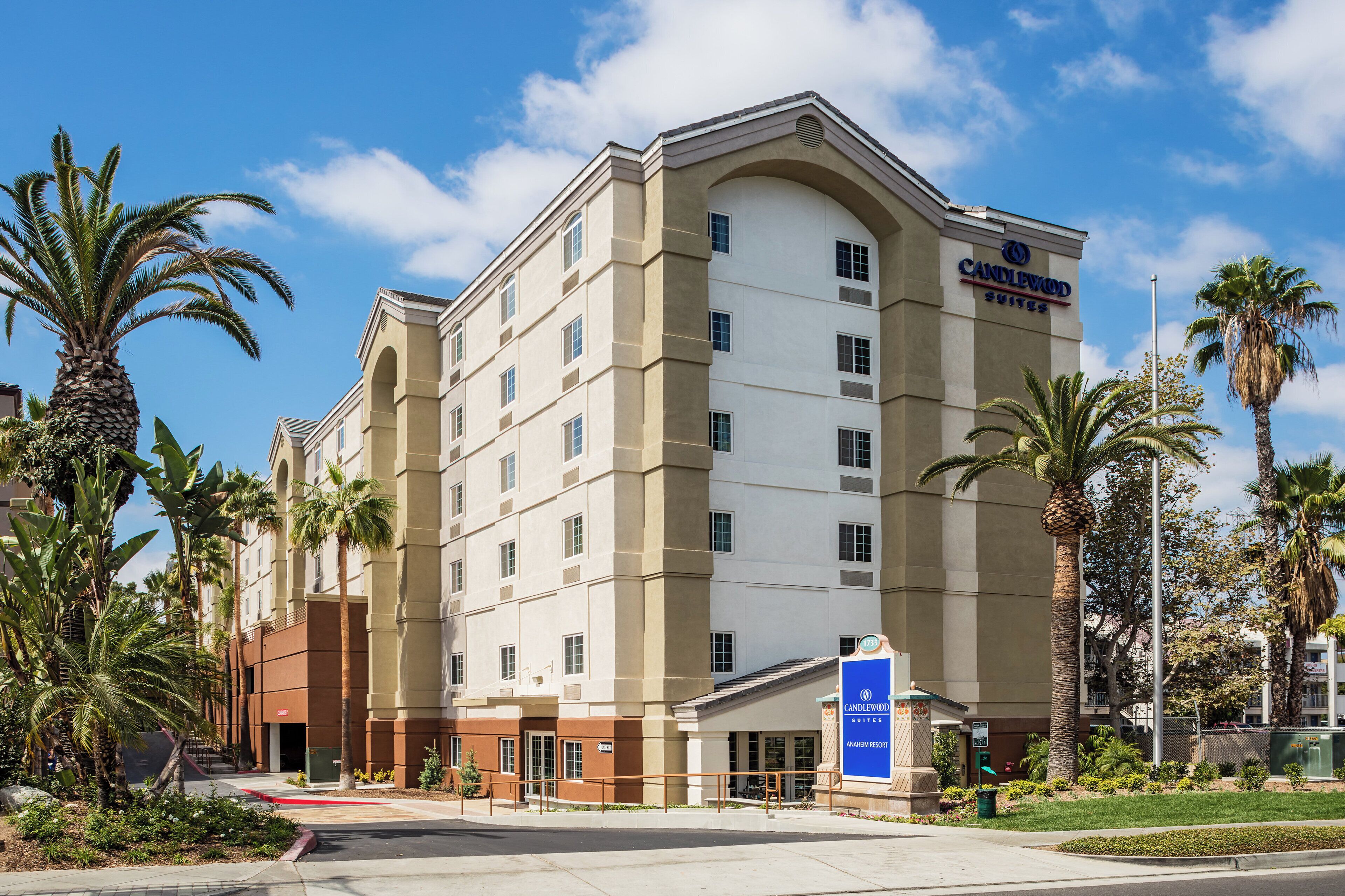 A multi-story hotel with a prominent entrance, palm trees, and a clear sky.