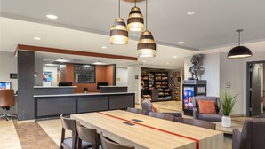 A modern hotel lobby with a reception desk, seating area, and a Disney-themed display. - Candlewood Suites Anaheim - Resort Area by IHG (Anaheim)