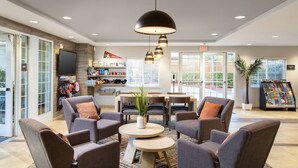A lobby with seating, a TV, a plant, and a magazine rack. - Candlewood Suites Anaheim - Resort Area by IHG (Anaheim)