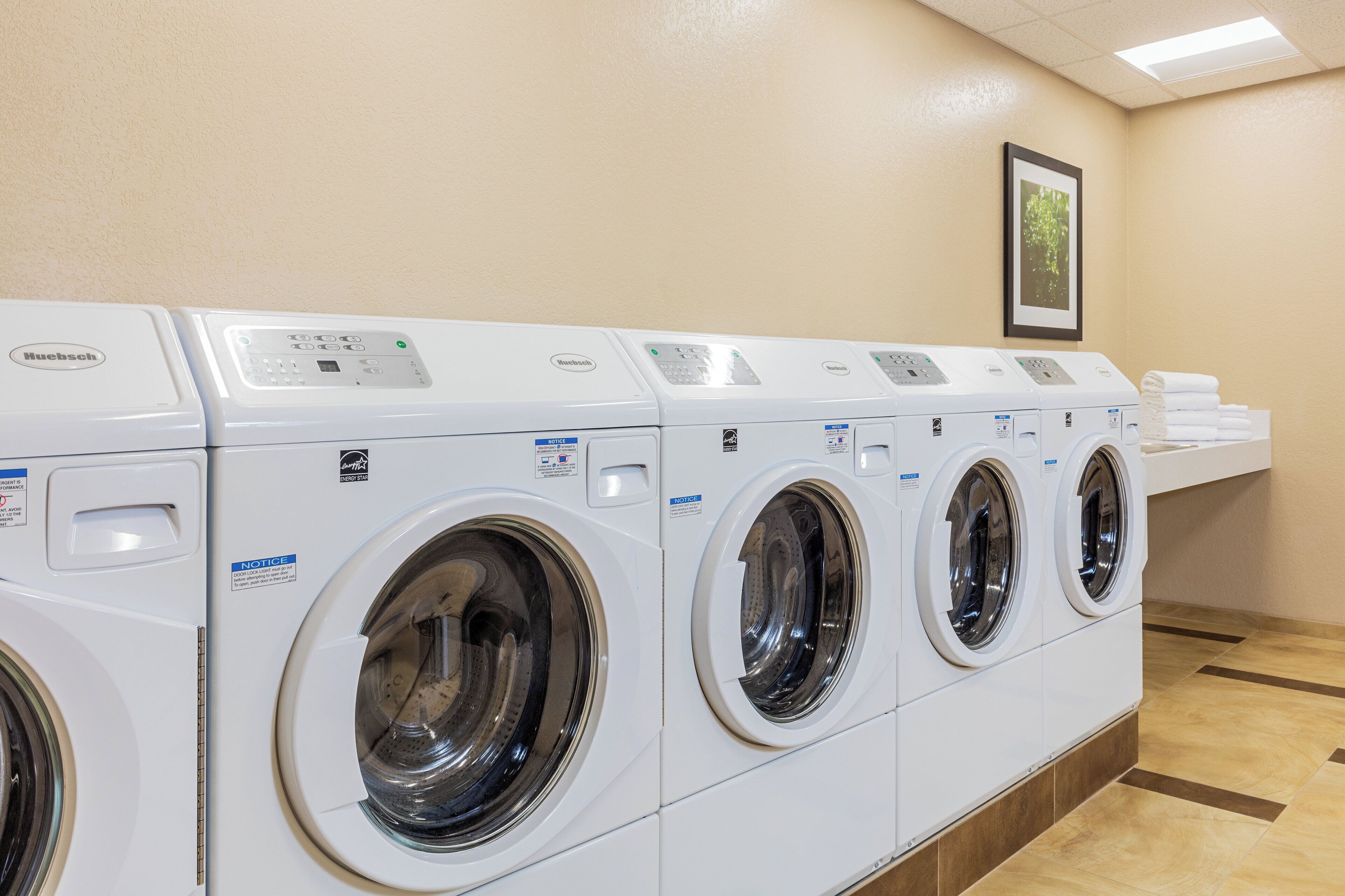 Een rij witte wasmachines met voorlaadklep in een commerciële omgeving.