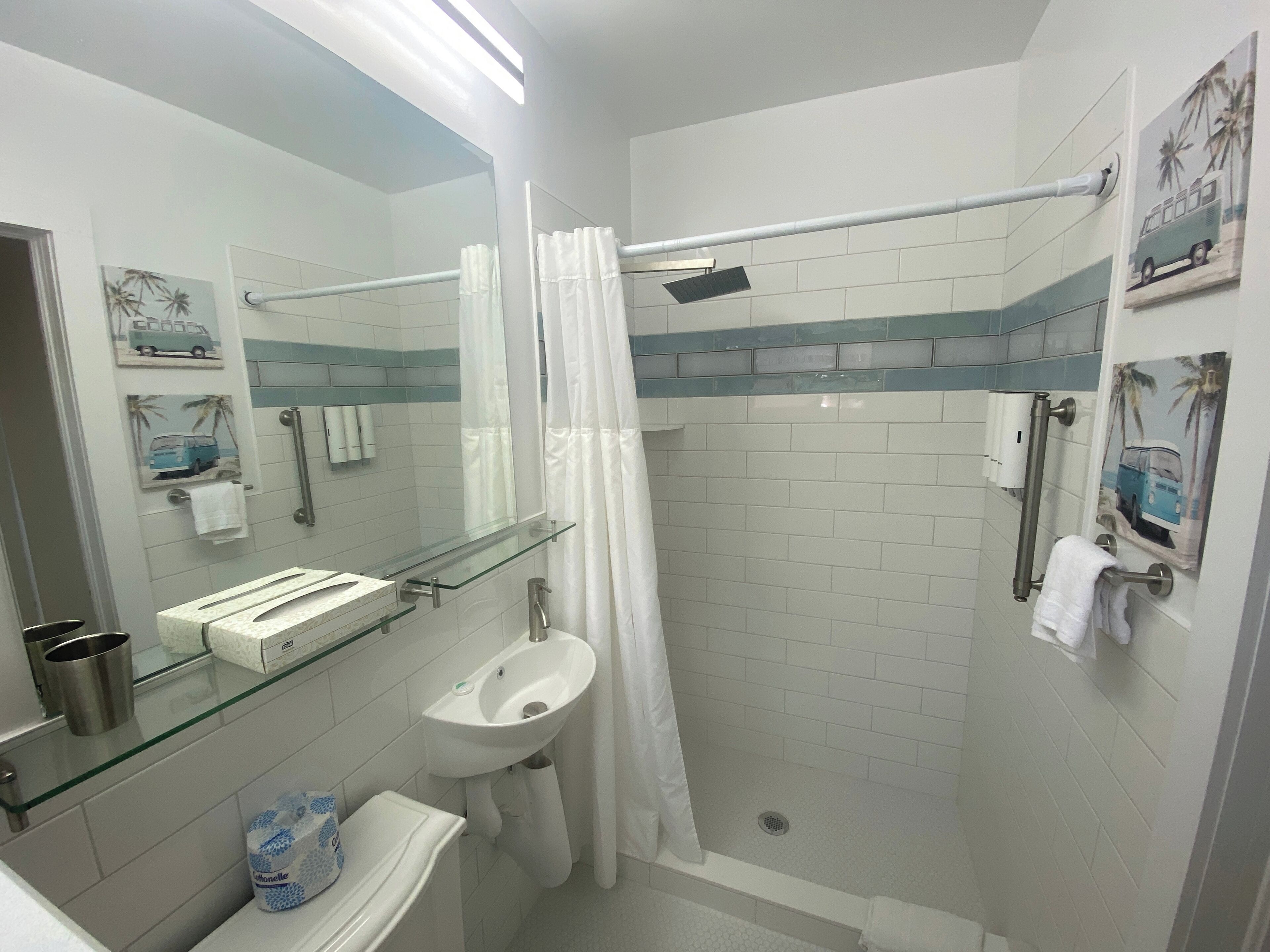 A modern bathroom with a glass shower enclosure, a white sink, and a mirror.