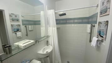 A modern bathroom with a glass shower enclosure, a white sink, and a mirror.