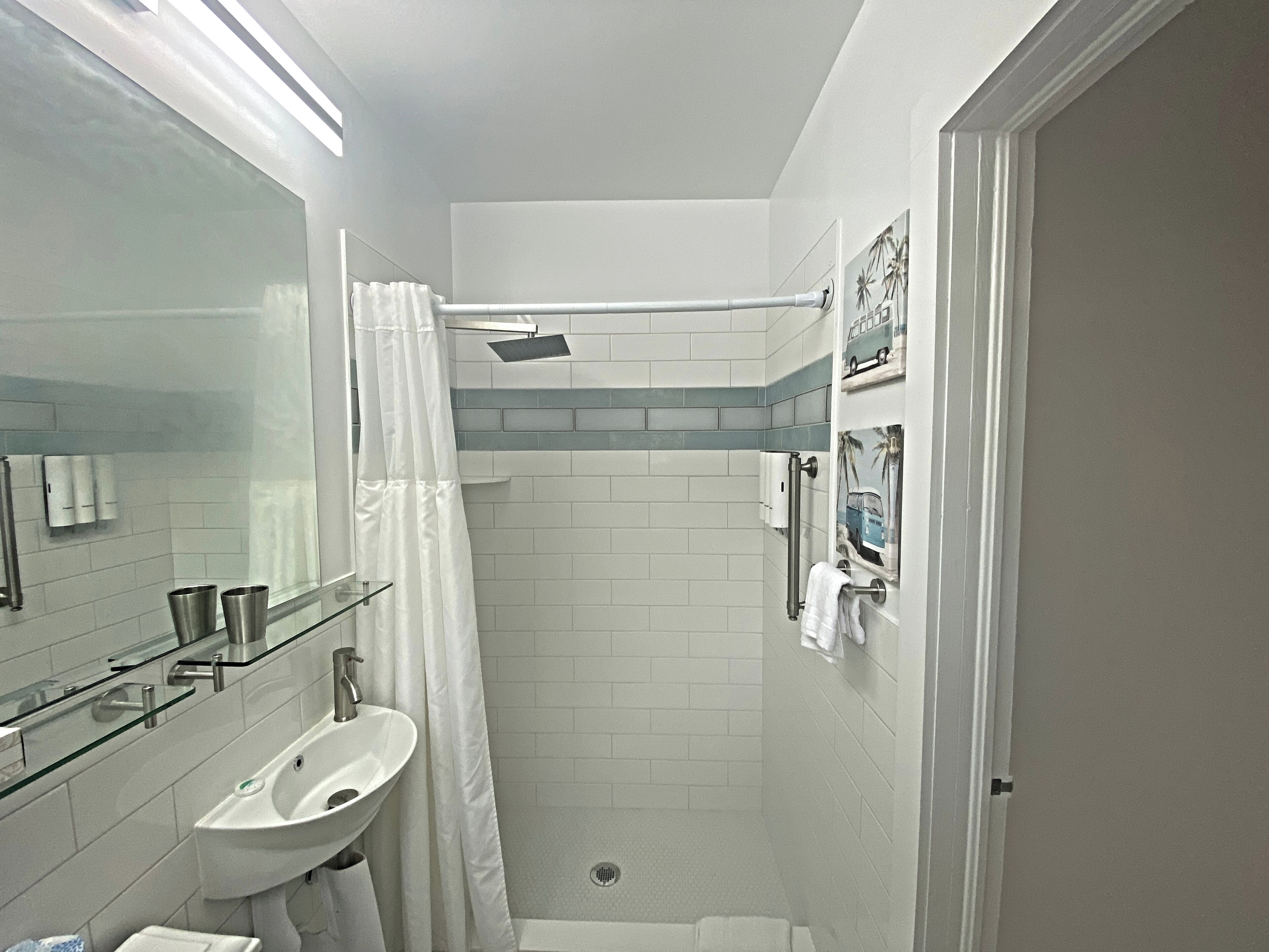 Un bagno moderno con box doccia in vetro, lavabo bianco e porta asciugamani.