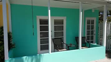 A covered porch with two doors and a small table with chairs.