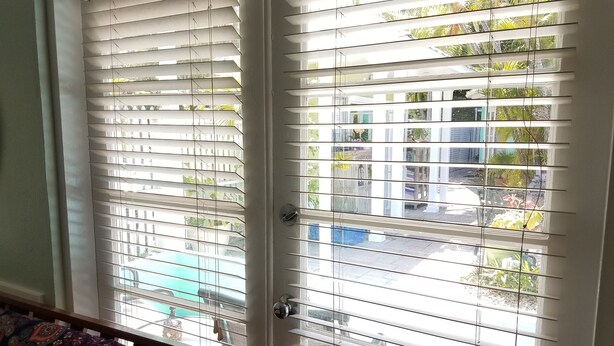 A room with a door featuring horizontal blinds, a visible outdoor view through the window, and a patterned carpet.