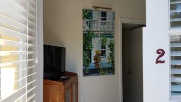 Um corredor com um armário de madeira, uma TV de tela plana e um quadro na parede retratando uma casa.