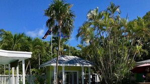 A pool area with a covered seating area, palm trees, and a small pavilion.