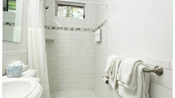 A small, white bathroom with a toilet, sink, and shower area.