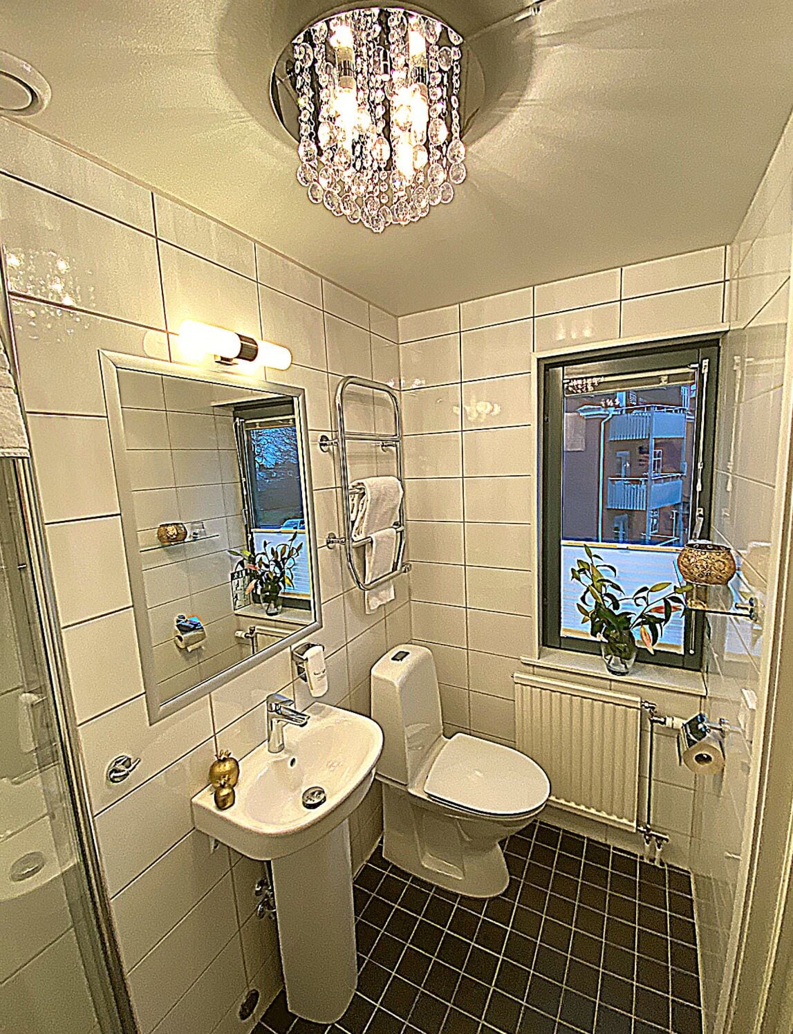 Un baño con lavamanos, inodoro y ventana con vista a un edificio.