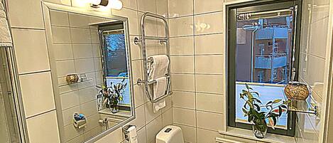 Un baño con lavamanos, inodoro y ventana con vista a un edificio.