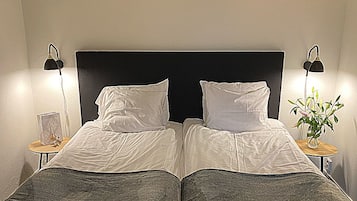 A double bed with a black headboard, two bedside tables with lamps, and a small plant on one table.