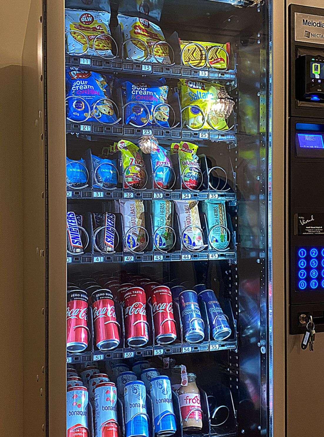 A vending machine with various snack and drink options, including chips, sodas, and energy drinks.