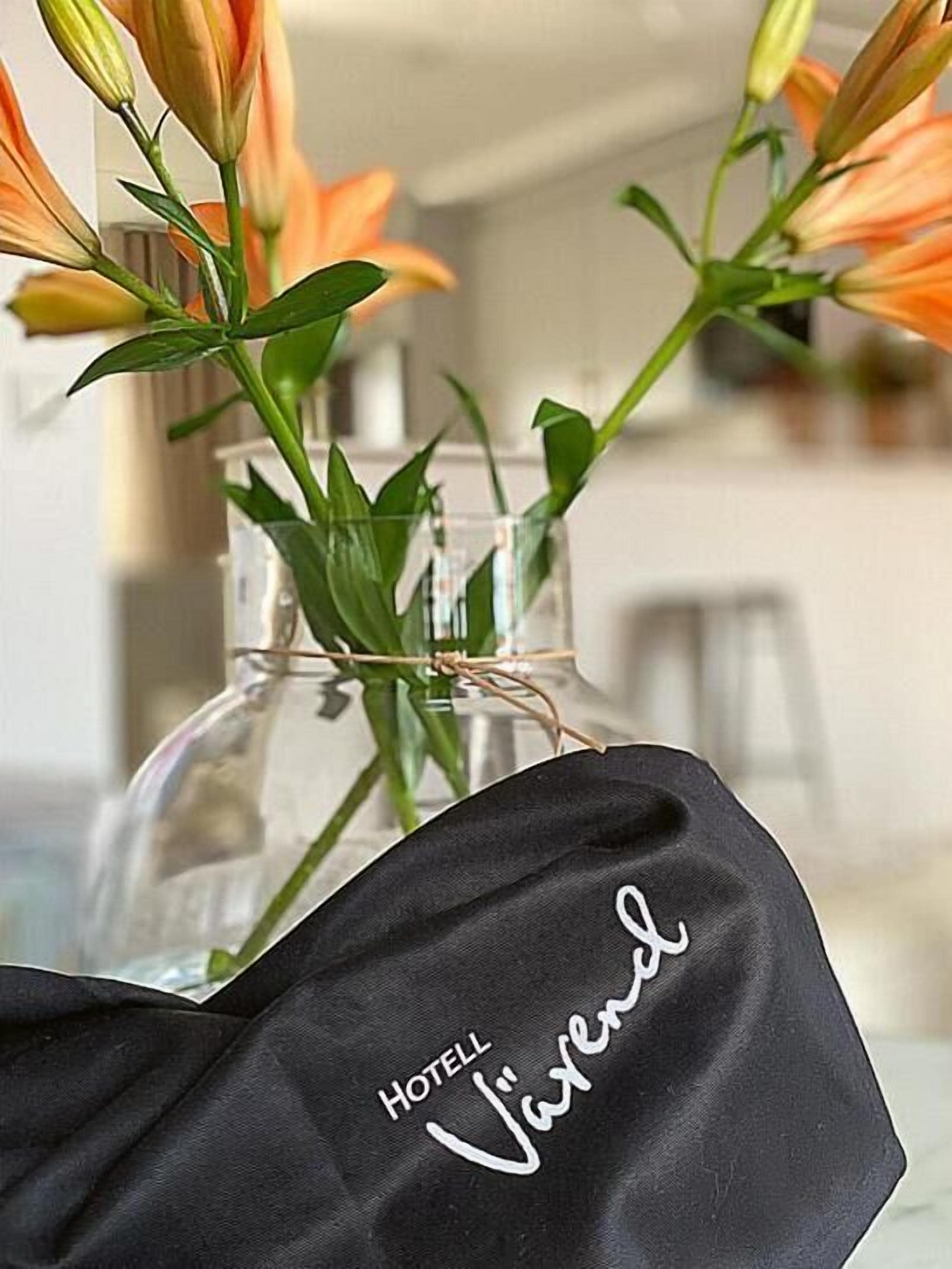 A clear glass vase with orange flowers, placed on a table.