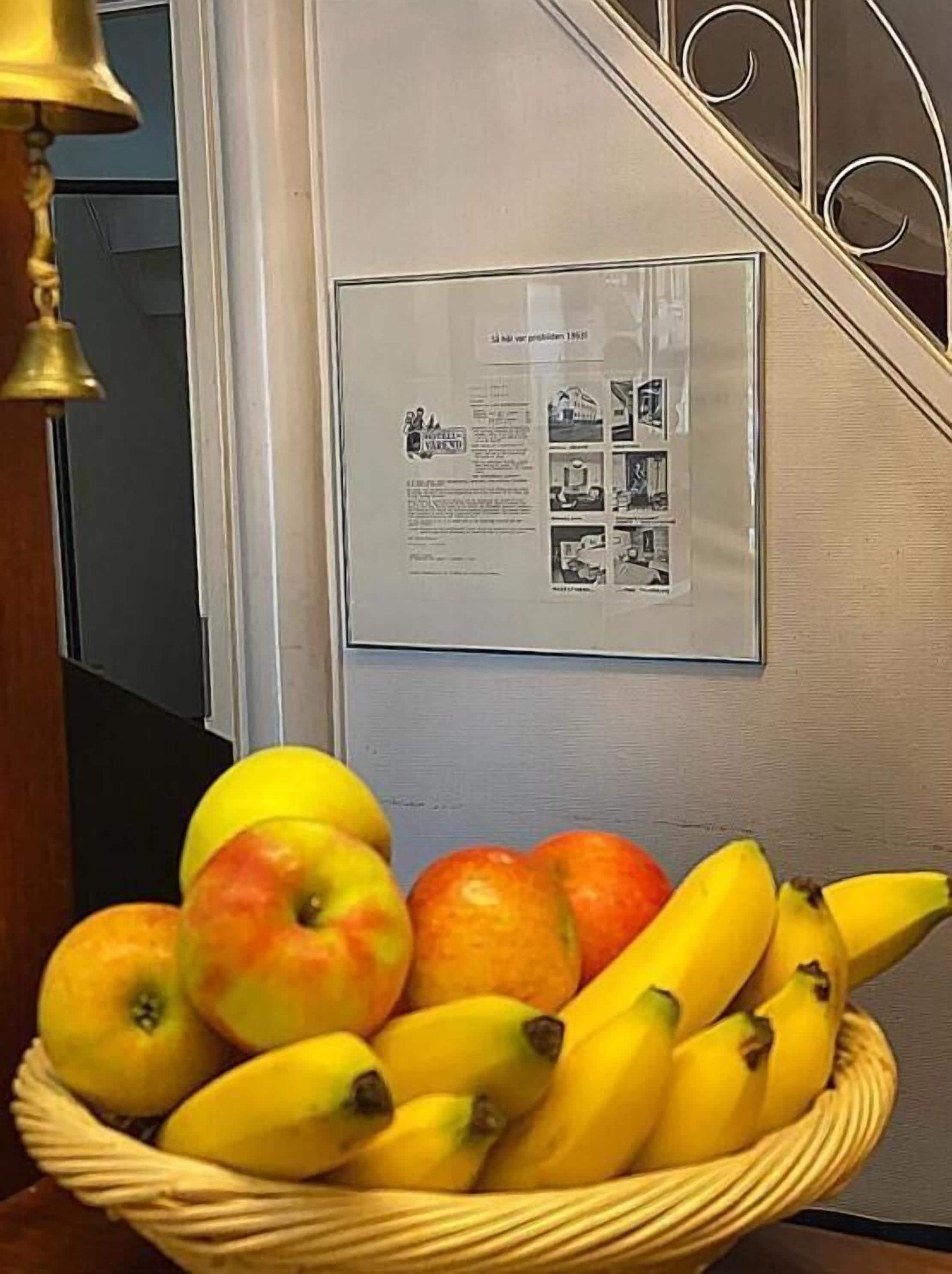 Una pantalla montada en la pared con un documento enmarcado y una cesta de fruta.