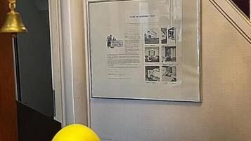 Una pantalla montada en la pared con un documento enmarcado y una cesta de fruta.