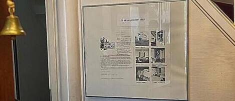 A wall-mounted display with a framed document and a basket of fruit.