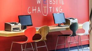 Un espace de travail équipé de deux ordinateurs, d’une imprimante et d’un bureau avec quatre chaises.