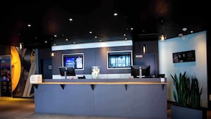 A reception desk with two monitors, a key box, and a potted plant. - ibis Hotel Köln Messe (Cologne)
