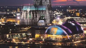 Une cathédrale historique, dotée de deux flèches jumelles et d’un grand dôme, avec une rivière en premier plan.