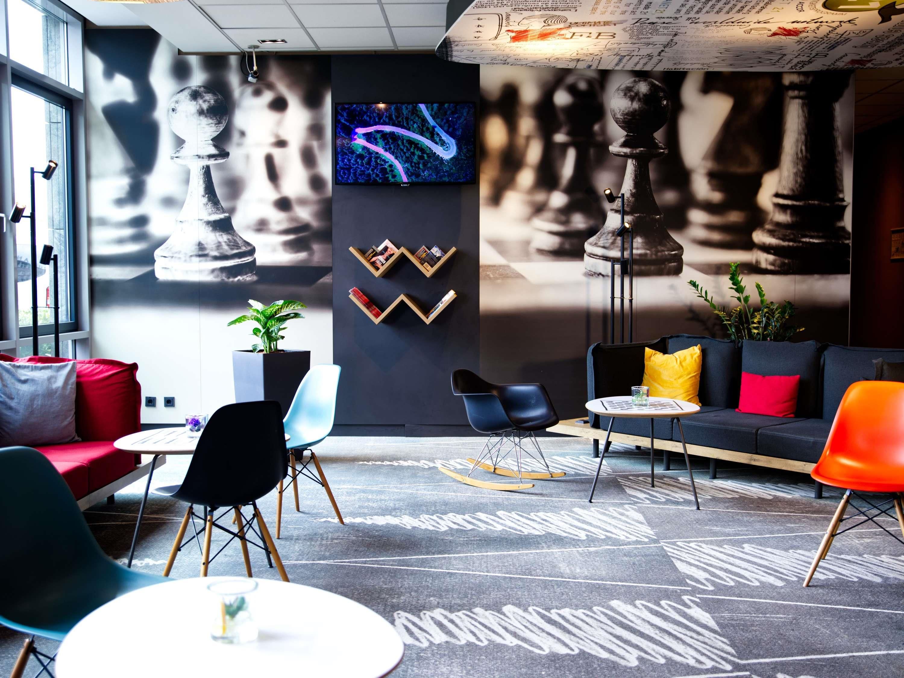 A modern lounge area with a chessboard, a large screen, and a cozy seating arrangement.