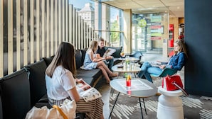 Een modern interieur met zithoeken, een glazen wand en een zichtbaar menubord.