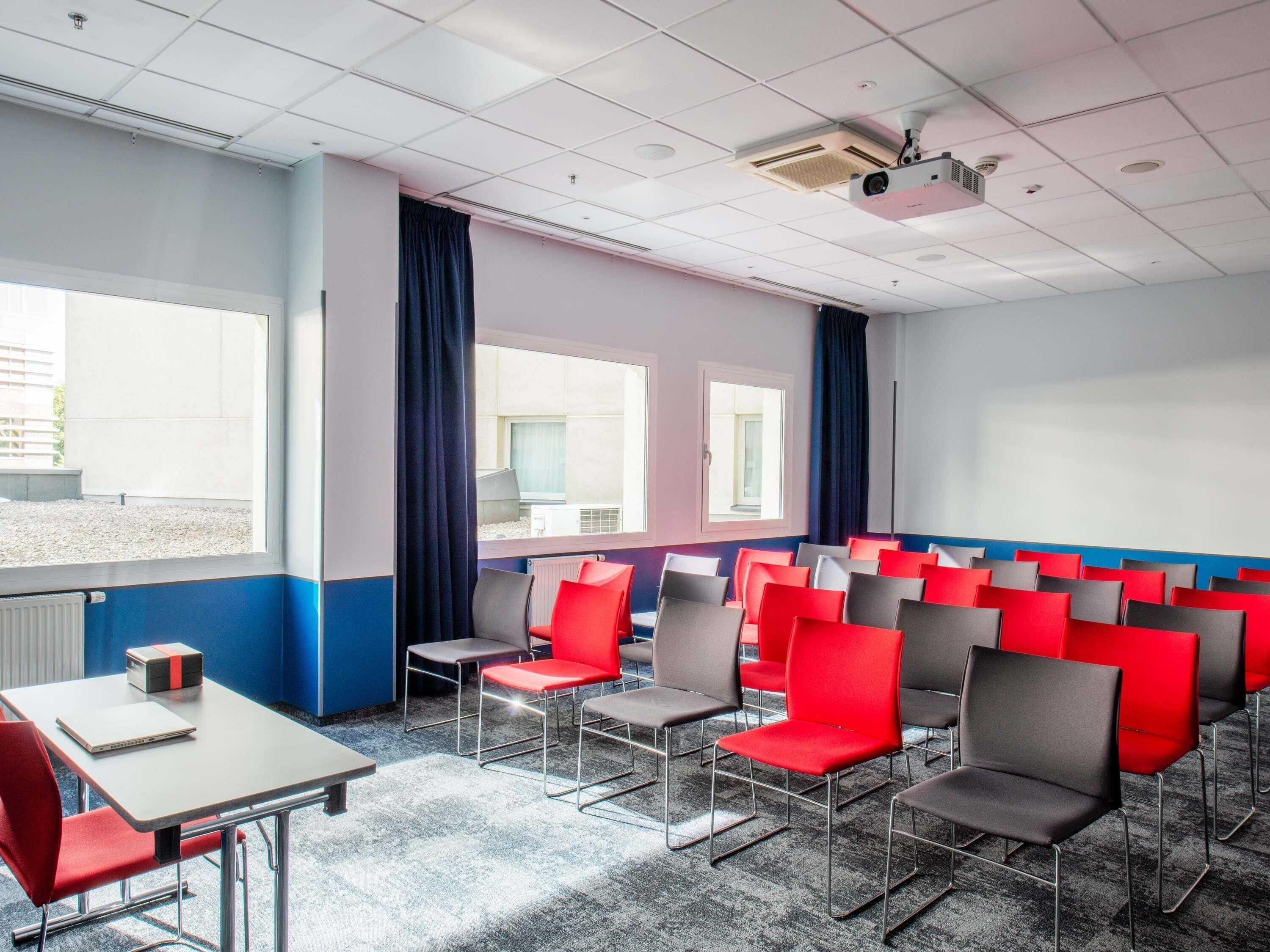 A conference room with rows of chairs, a projector, and a table with a laptop.