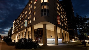Een hotel met modern design, met een opvallend ‘ibis’ logo, een ruime entree met glazen gevel en een reeks ramen.