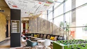 Een moderne lobby met een tafelvoetbaltafel, een zithoek en een muur met borden met wegwijzers.