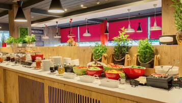 Zona de bufé con diversas opciones de comida y un cartel que indica 'Bis Kitchen'.