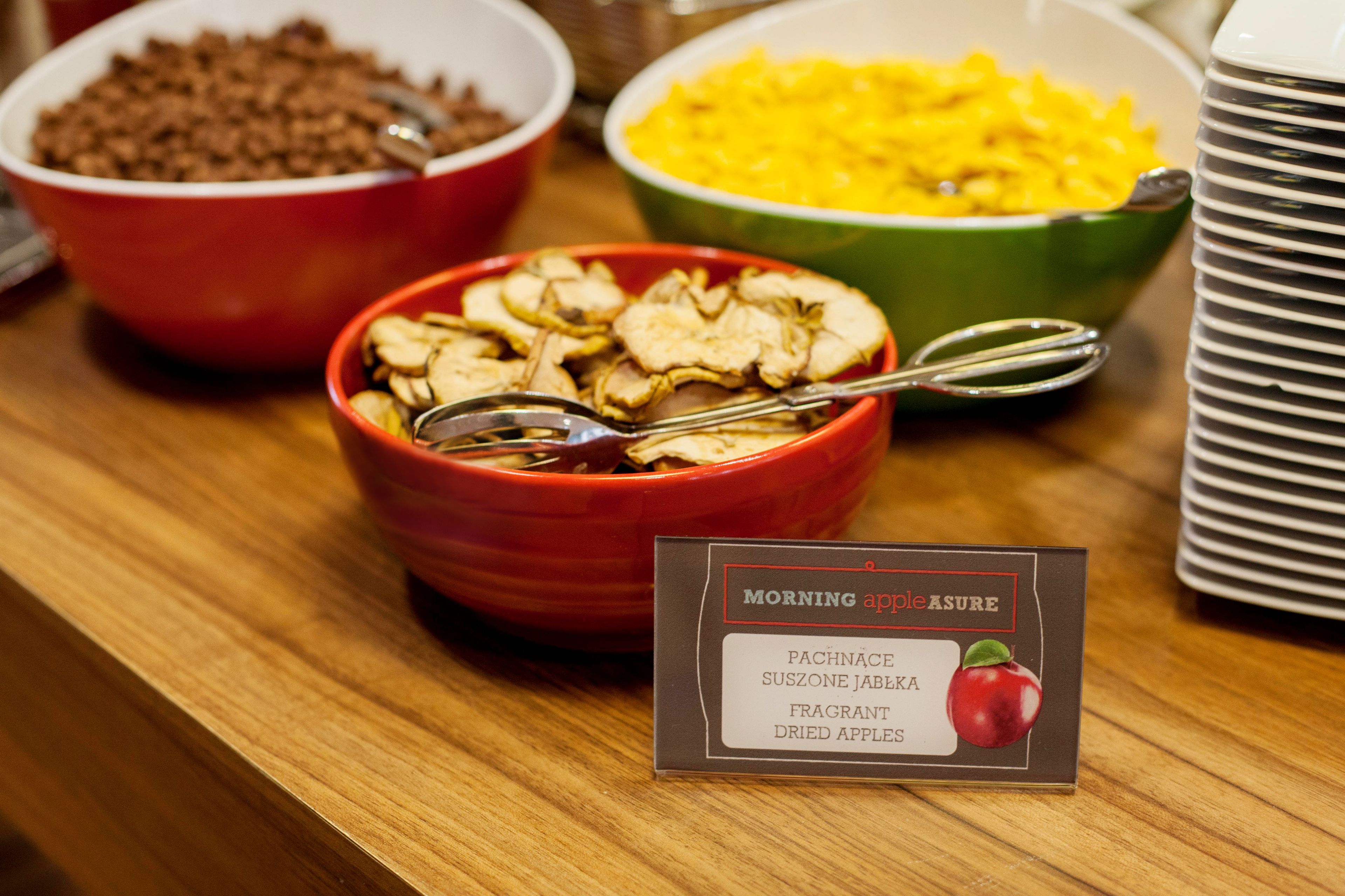 A breakfast buffet with various food items including dried apples, cereal, and scrambled eggs.