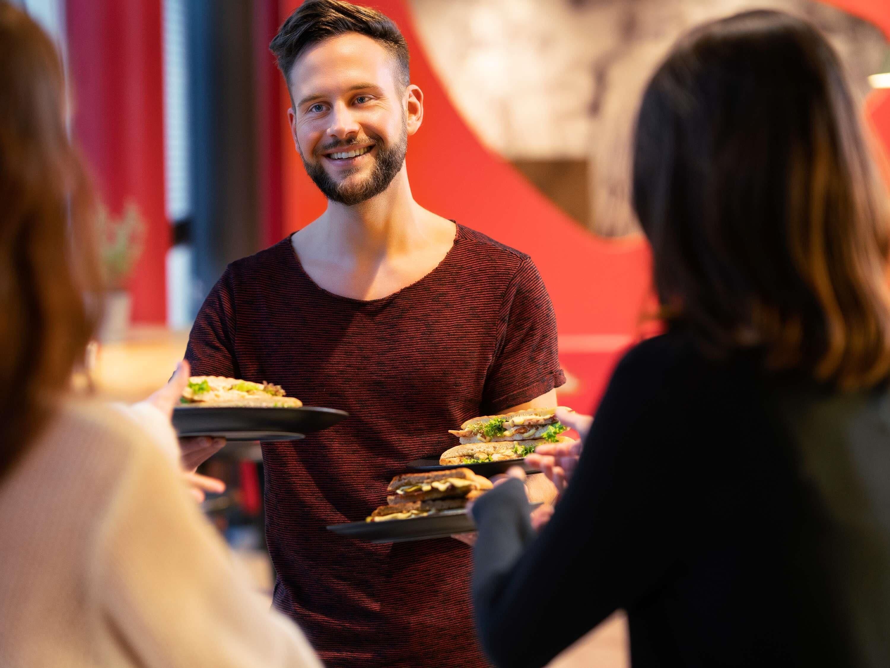 A person serving food to guests in a restaurant setting.
