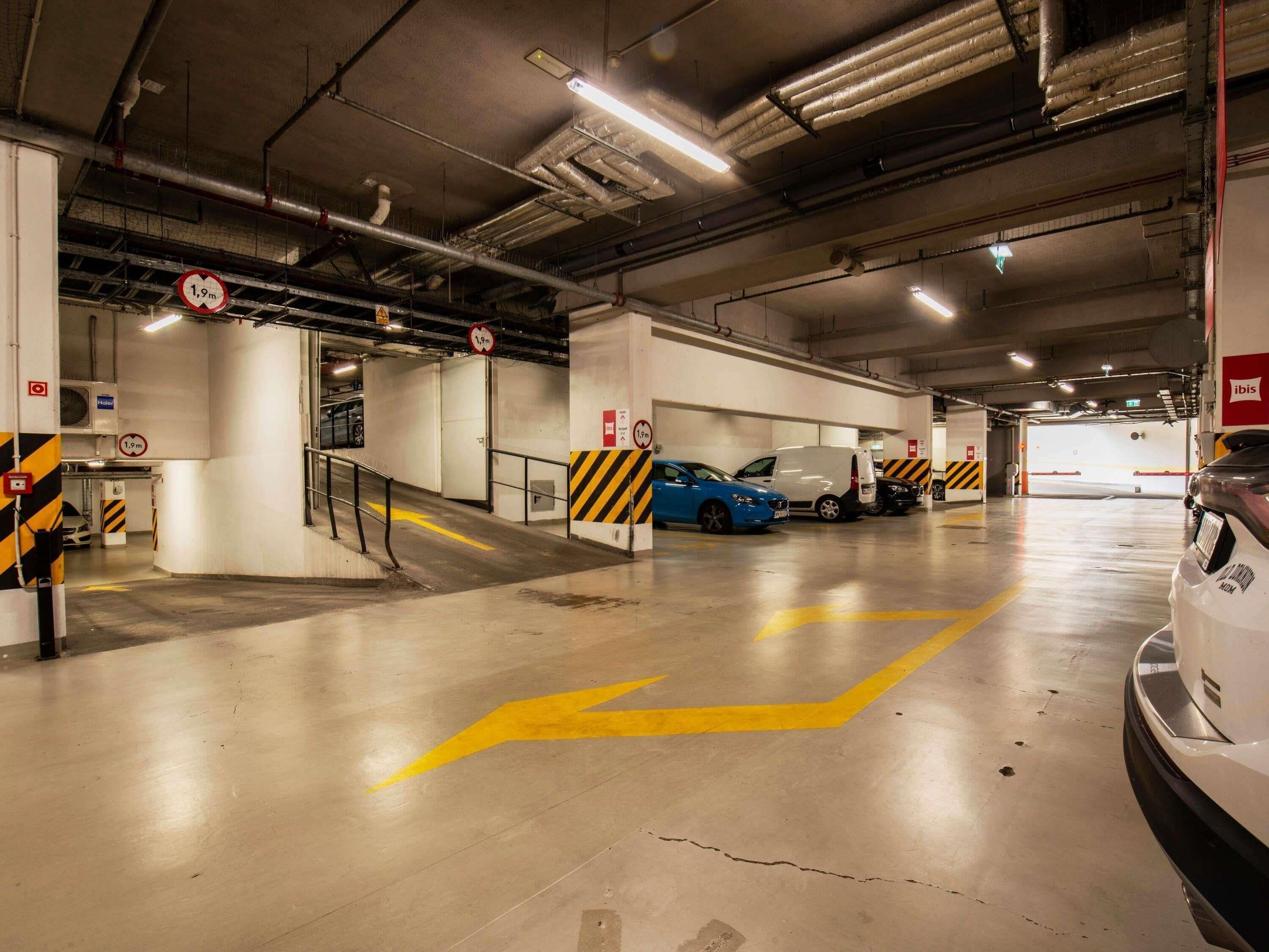 A multi-level parking garage with directional arrows on the floor, a white van, and a blue car parked.