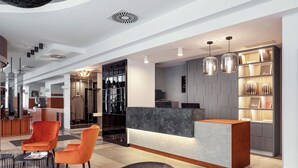 A modern hotel lobby with a reception desk, seating area, and a bar. - Hotel Astoria (Prague)