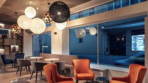 A modern lounge area with seating and tables, large windows, and decorative spherical pendant lights. - Hotel Astoria (Prague)