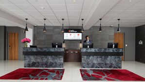 A reception area with two reception desks, a digital screen displaying information, and a wooden door. - Rydges Latimer Christchurch (Christchurch)