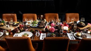 A dining table set with multiple dishes, glasses, and cutlery, surrounded by leather chairs. - Rydges Latimer Christchurch (Christchurch)