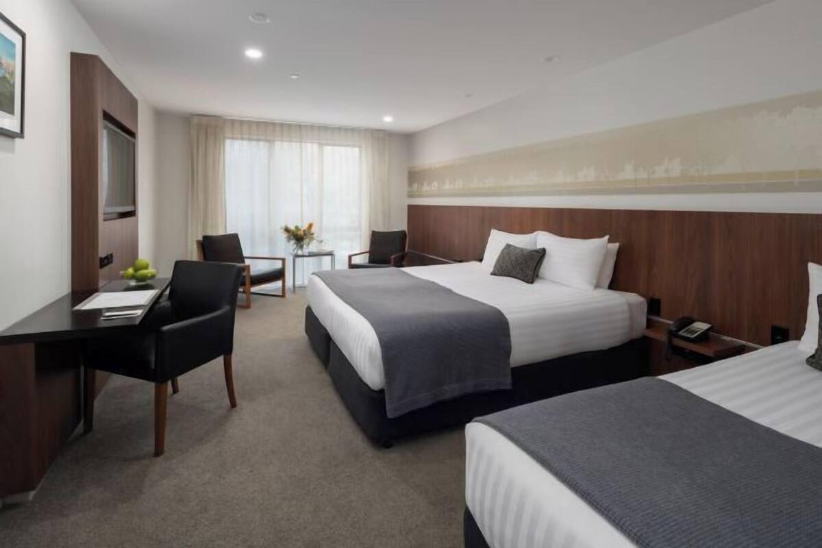 Una habitación de hotel con dos camas, un escritorio y una silla.