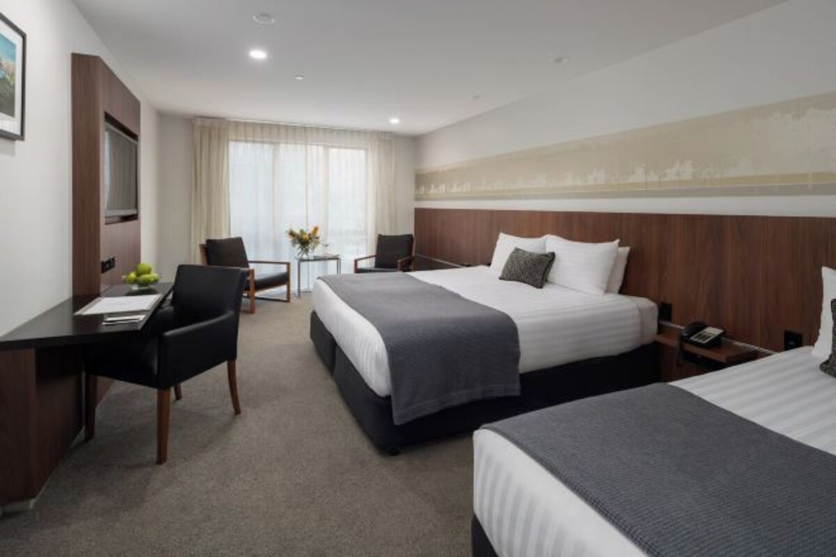 Une chambre d’hôtel avec deux lits, un bureau et une chaise.