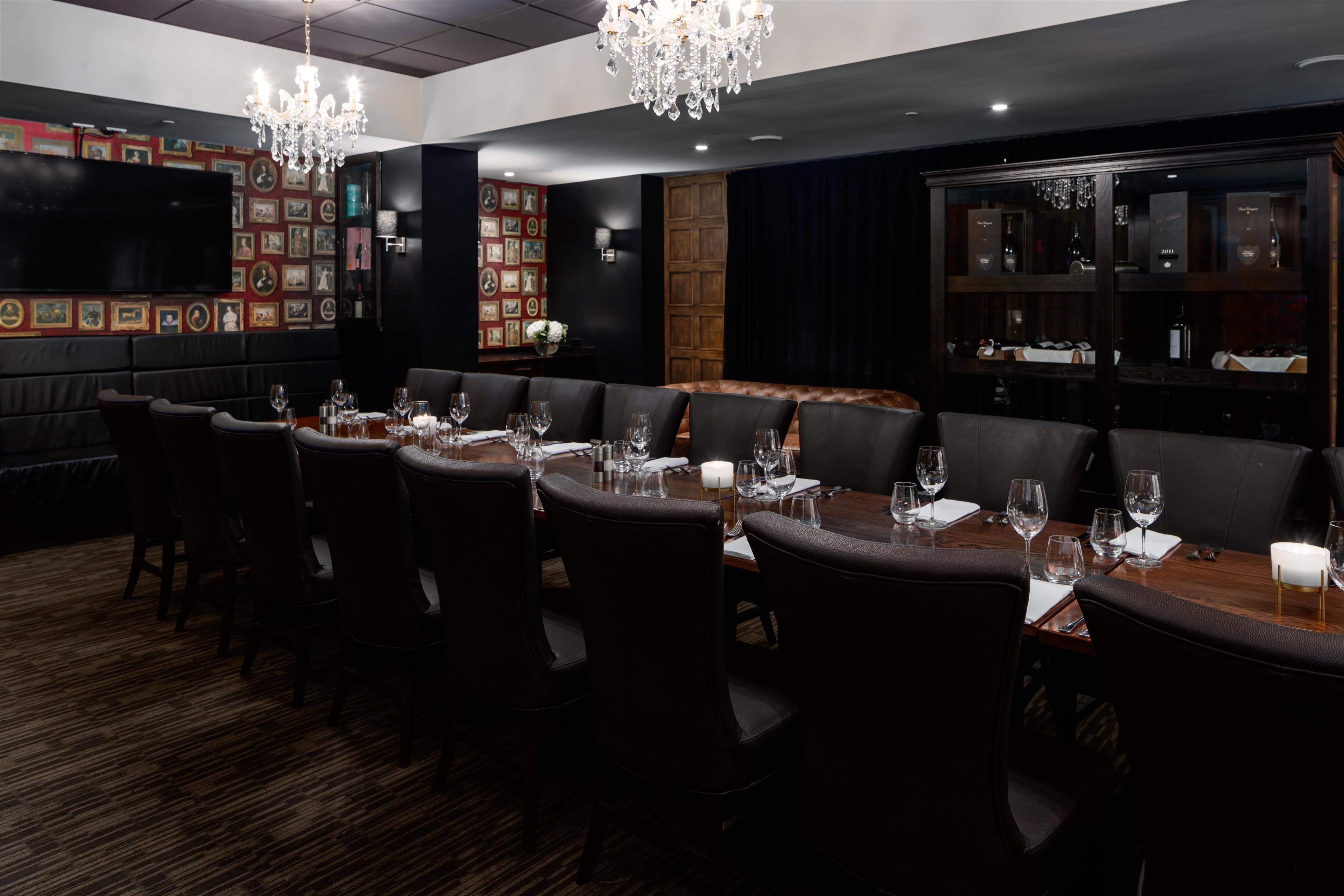 A restaurant with a long dining table, multiple chairs, and a chandelier.