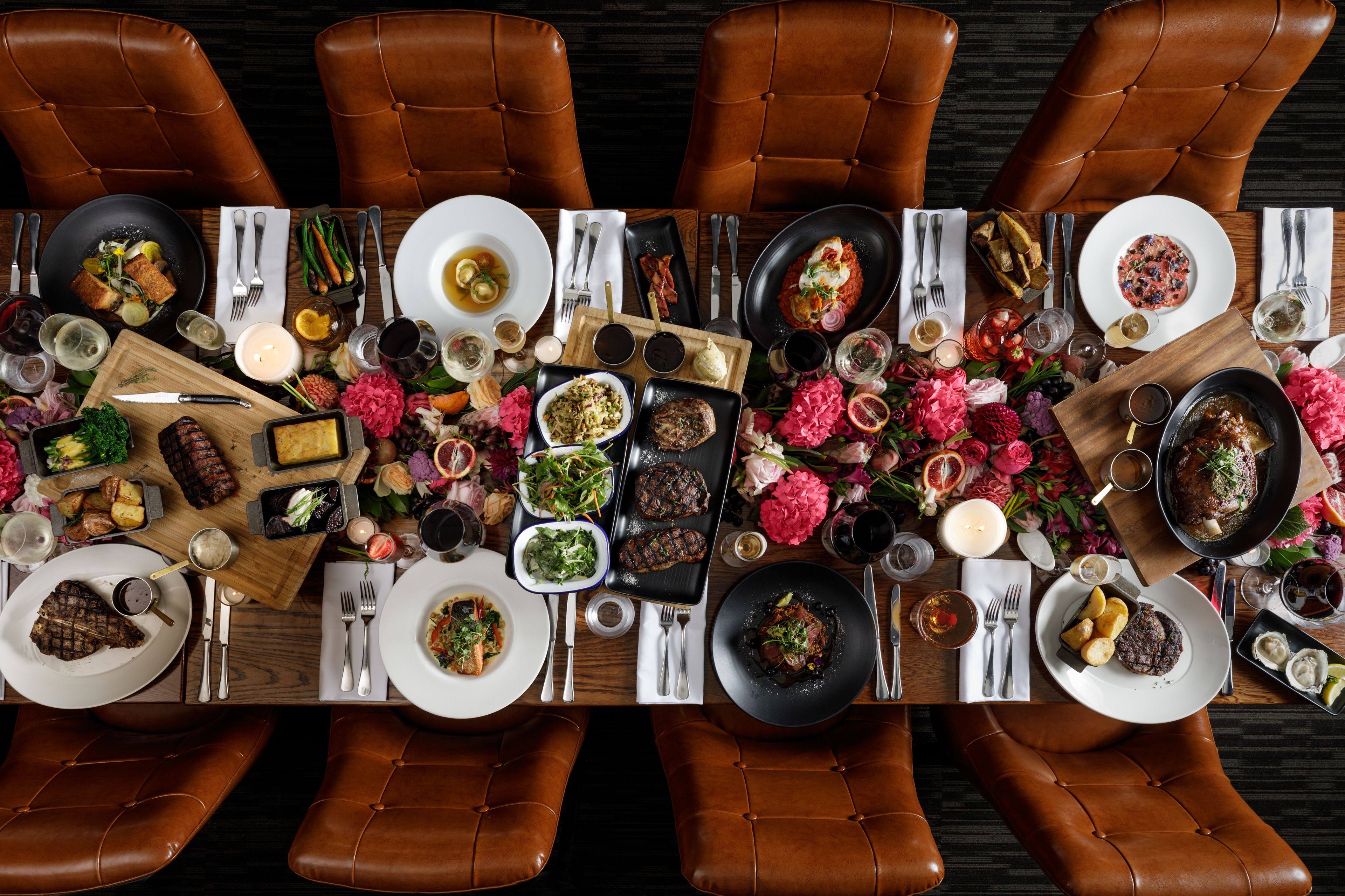 A dining table set for a meal with various dishes, utensils, and a floral centerpiece.