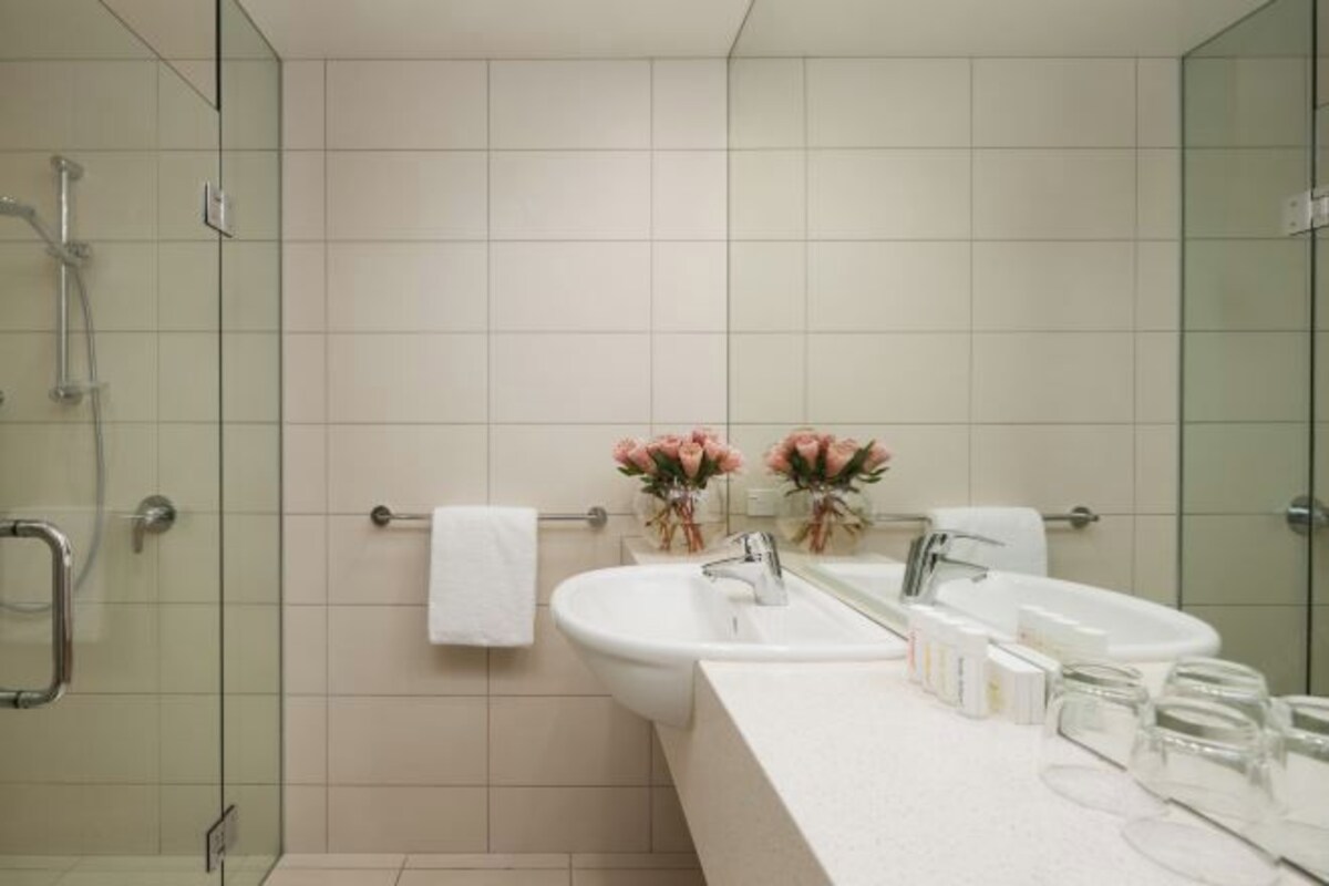 Une salle de bain moderne dotée d’une douche à parois de verre, de deux lavabos et d’un meuble-lavabo avec des articles de toilette.