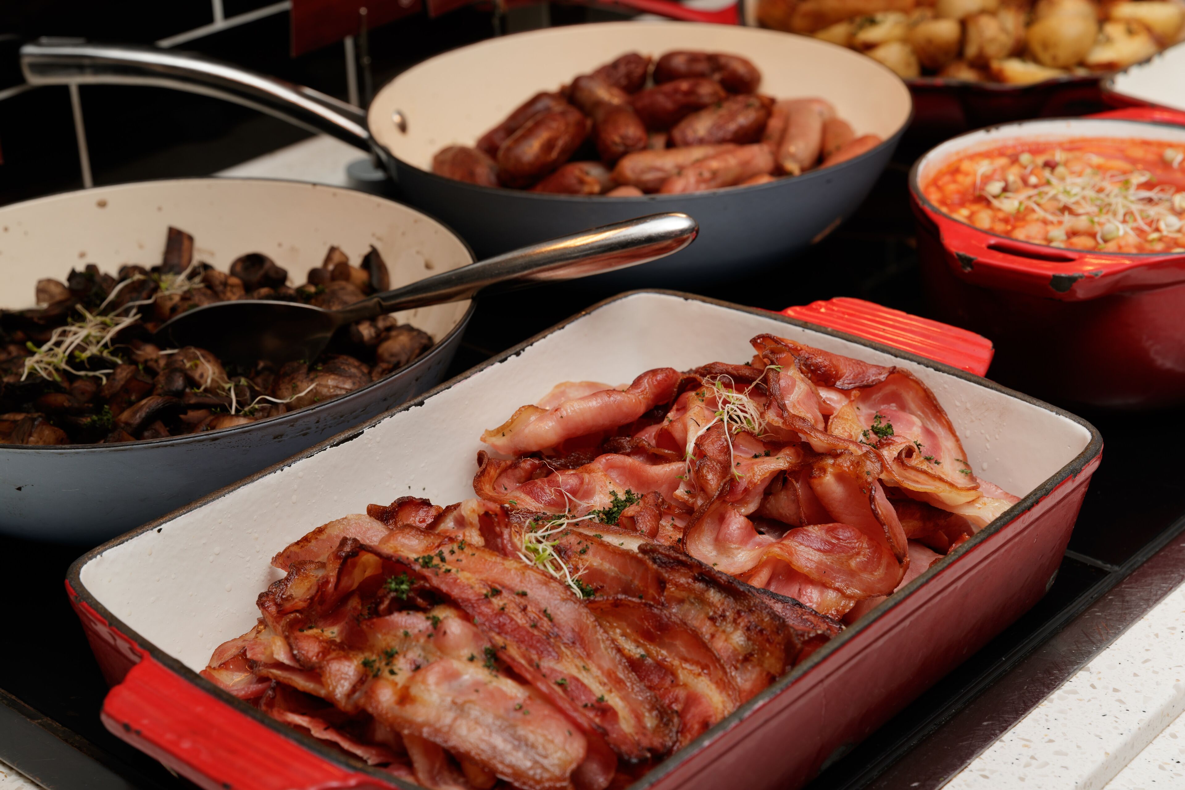 A variety of cooked meats and vegetables in different pots and pans on a stove.