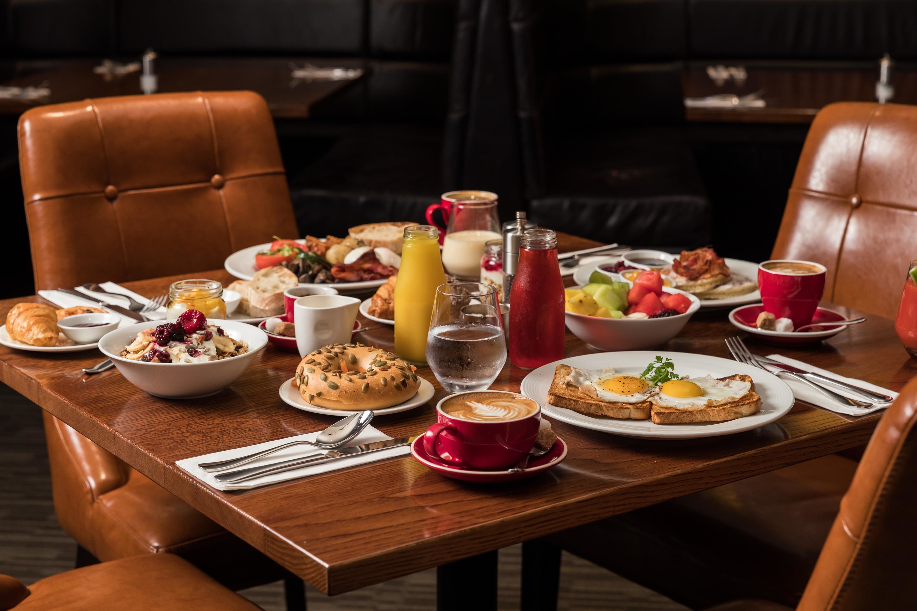 Una mesa de comedor con desayuno, que incluye huevos, tostadas, pasteles y bebidas.