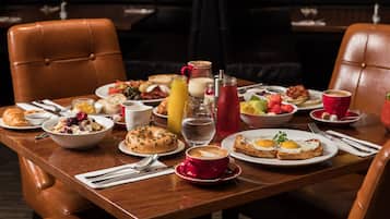 Una mesa de comedor con desayuno, que incluye huevos, tostadas, pasteles y bebidas.