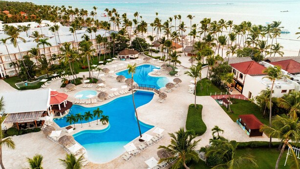 A resort with a large pool area, multiple lounge chairs, and a beach.