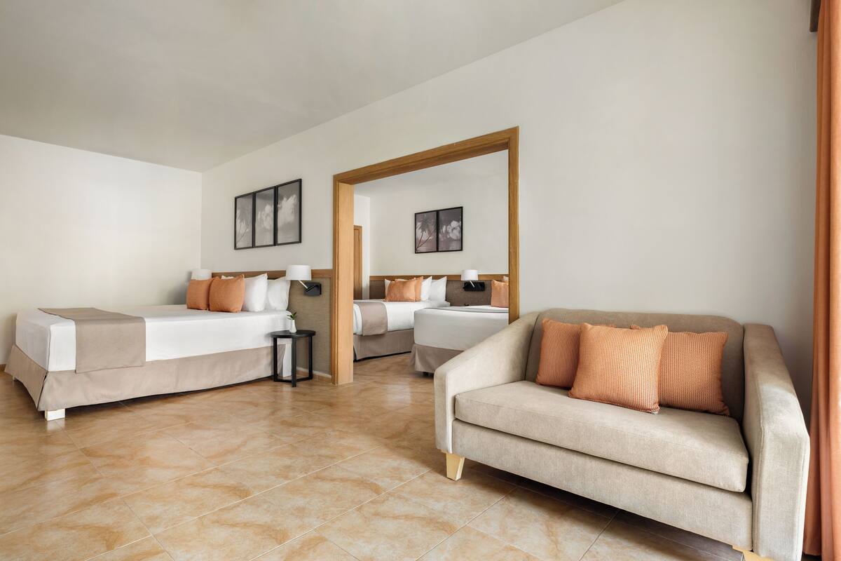 Habitación de hotel con dos camas, un sofá y un espejo grande.